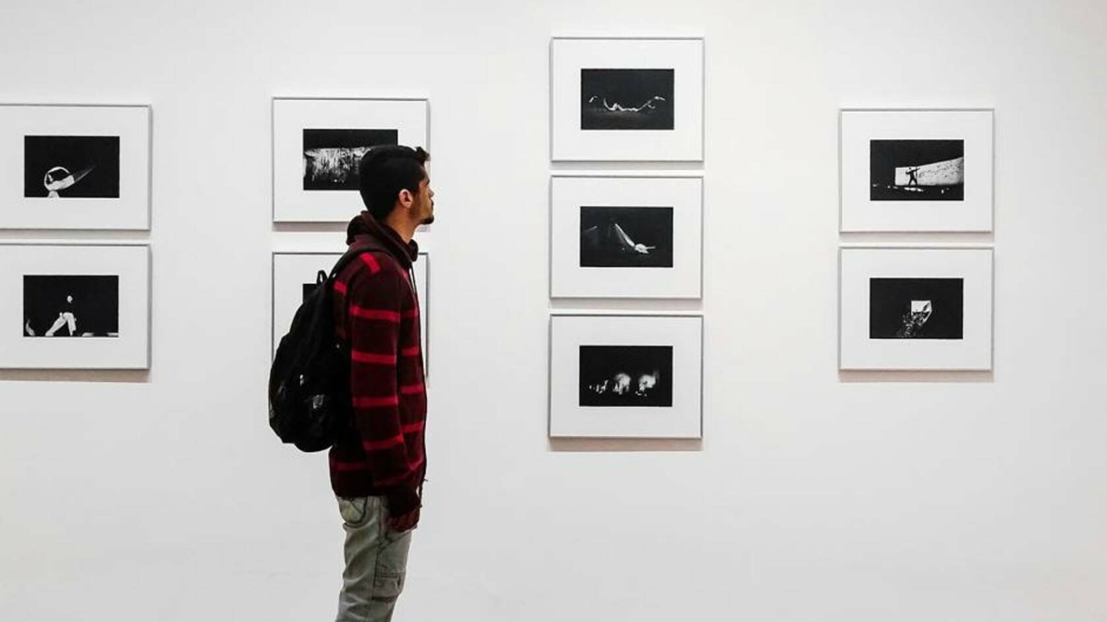 Foto “Man Standing Beside White Painted Wall” von Matheus Viana