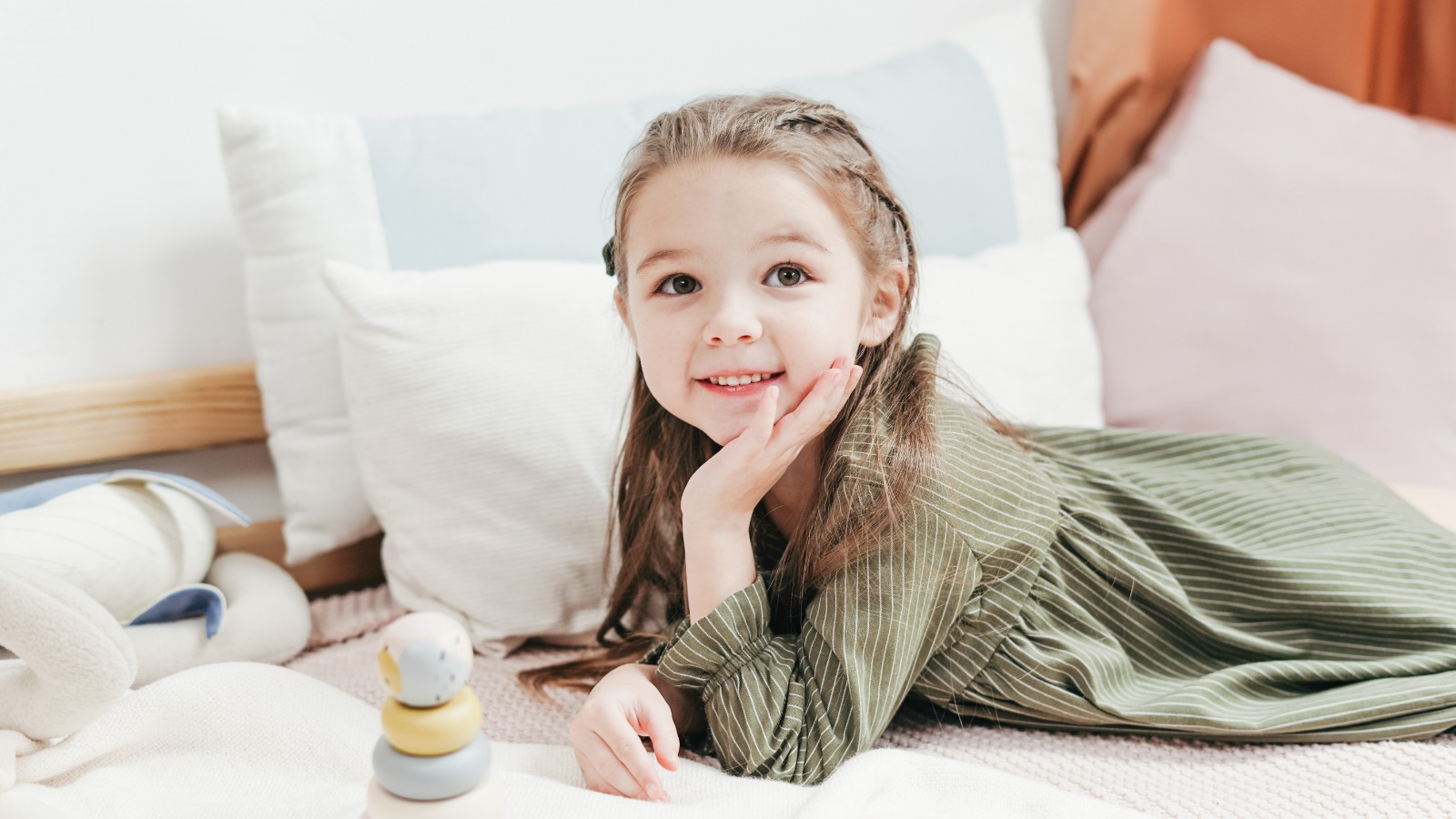 Foto “Smiling Girl in Green and White Stripe Long Sleeve dress Lying on Bed” von cottonbro